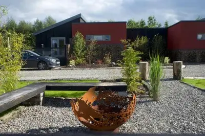 a garden with a large flower pot in front of a house at Byre 1 InThePark in Stirling