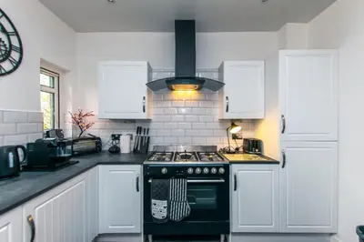 a kitchen with white cabinets and a stove top oven at Cosy & Central 2BD Apartment Milngavie, Glasgow in Milngavie