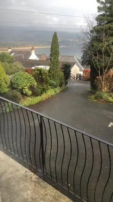 a black fence with a view of a house at Belvedere in Brodick