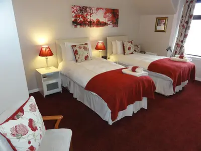 a hotel room with two beds with red sheets at Belvedere in Brodick