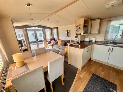 a kitchen and living room with a wooden table in a kitchen at Swift Moselle 2 Bedroom Caravan Located in Uddingston, Glasgow at Maryville Caravan Site in Uddingston
