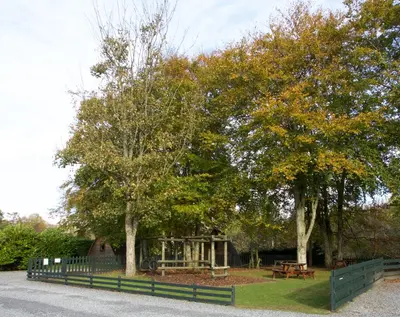 a fence next to two trees and a bench at Braidhaugh Holiday Lodge and Glamping Park in Crieff