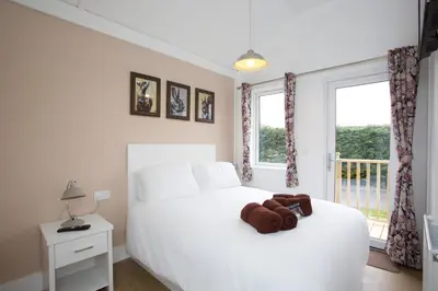 a bedroom with a white bed and a window at Braidhaugh Holiday Lodge and Glamping Park in Crieff