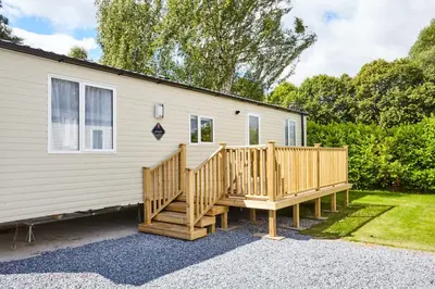 a house with a wooden deck next to a house at Braidhaugh Holiday Lodge and Glamping Park in Crieff