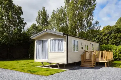 a white tiny house with a porch in a yard at Braidhaugh Holiday Lodge and Glamping Park in Crieff