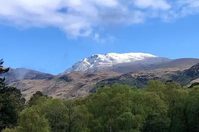 a snow covered mountain with trees in front of it at Cozy Loch Lomond Lodge 27, Rowardennan in Rowardennan