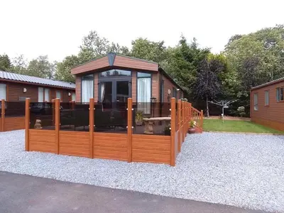 a house with a wooden fence with a gazebo at Silver Birch Lodge in Auchterarder