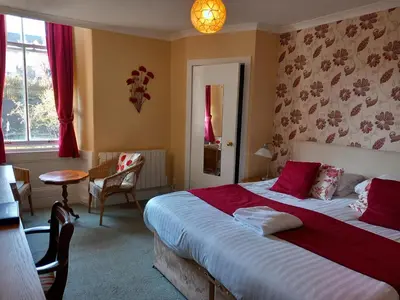 a bedroom with a large bed with red sheets at The Ardyne Guest House in Rothesay