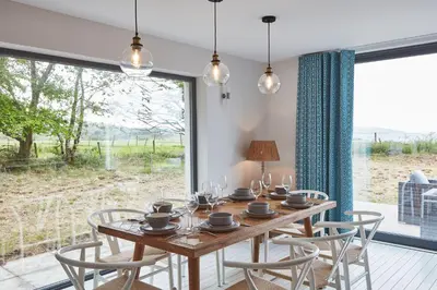 a dining room with a table and chairs and a large window at Beach House in Pennygown