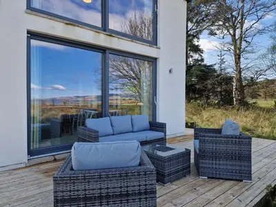 a patio with a couch and chairs on a deck at Beach House in Pennygown