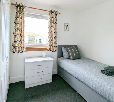 a bedroom with a bed and a dresser and a window at Campbeltown Loch in Campbeltown