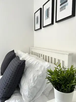 a white bed with white pillows and a plant at 3 bedroom - 2 bathroom Townhouse in Corstorphine Near Murrayfield Stadium - Direct Bus To Edinburgh City Centre in 20 Minutes - Two Private Parking Spaces - Private Sunny Garden - Recently Refurbished in Edinburgh