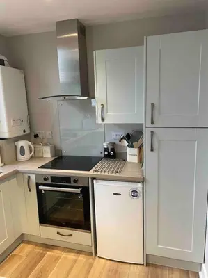 a kitchen with white cabinets and a stove top oven at 34 James St cosy 2 bedroom, ground floor apartment, garden in Helensburgh