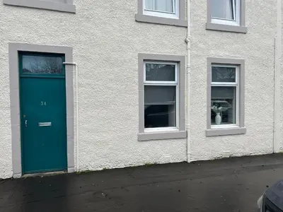 a building with a green door and two windows at 34 James St cosy 2 bedroom, ground floor apartment, garden in Helensburgh