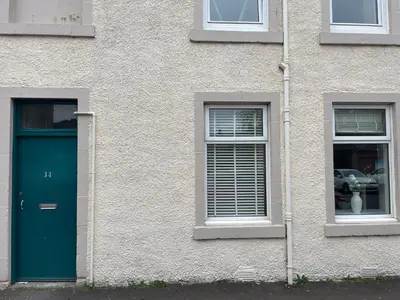 a building with a green door and two windows at 34 James St cosy 2 bedroom, ground floor apartment, garden in Helensburgh