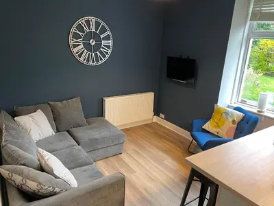 a living room with a couch and a clock on the wall at 34 James St cosy 2 bedroom, ground floor apartment, garden in Helensburgh