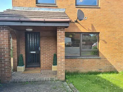 a brick house with a black door and a window at Travel Host 3 BEDROOM HOUSE WITH FREE PARKING in Nitshill