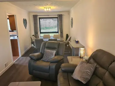 a living room with couches and a dining room at Travel Host 3 BEDROOM HOUSE WITH FREE PARKING in Nitshill