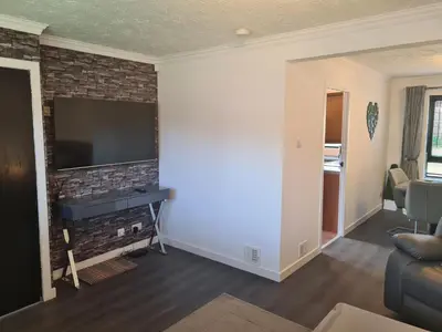 a living room with a tv on a brick wall at Travel Host 3 BEDROOM HOUSE WITH FREE PARKING in Nitshill