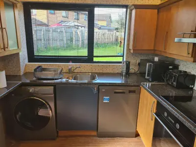 a kitchen with a washing machine and a sink at Travel Host 3 BEDROOM HOUSE WITH FREE PARKING in Nitshill