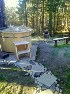 a bath tub and a bench in a park at Loch Aweside Forest Cabins in Dalavich