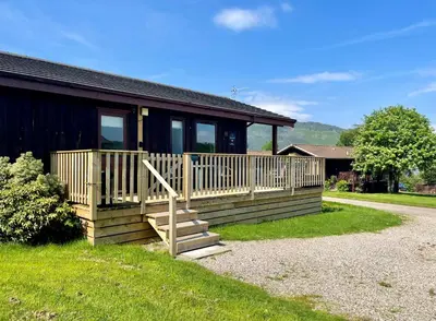 a house with a wooden porch and stairs to it at Blairlagan Lodge in Hunters Quay