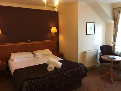 a hotel room with a bed and a chair at The Winnock Hotel in Drymen