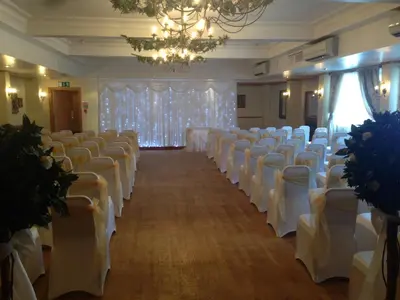 a room with rows of white chairs and a chandelier at The Winnock Hotel in Drymen