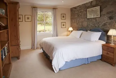a bedroom with a large bed and a stone wall at Port na Mine in Bonawe