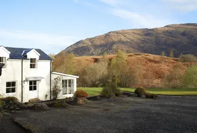 a white house with a mountain in the background at Port na Mine in Bonawe