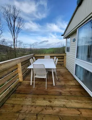 a wooden deck with a white table and chairs on it at FAB Caravan Holiday Home in Colmonell