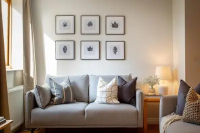a couch in a living room with pictures on the wall at Stunning 2 bed flat with parking, and garden with mountain views in Crieff