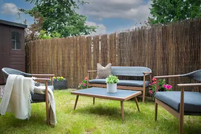 a backyard with two chairs and a table and a fence at Stunning 2 bed flat with parking, and garden with mountain views in Crieff