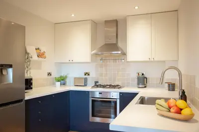 a kitchen with blue cabinets and a bowl of fruit on a counter at Stunning 2 bed flat with parking, and garden with mountain views in Crieff
