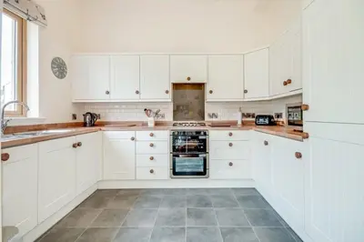 a kitchen with white cabinets and a tile floor at Kinnen Cottage in Creetown