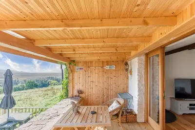 a wooden room with a table and a television at The Old Barn - cottage with spectacular lake view in Port of Menteith