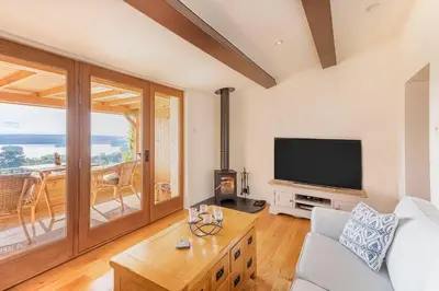 a living room with a couch and a television at The Old Barn - cottage with spectacular lake view in Port of Menteith