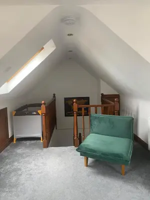 a room with a green chair in a attic at Cosy 2 bedroom home with free parking near city in Edinburgh