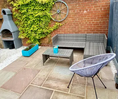 a patio with a bench and a table and a brick wall at Cosy 2 bedroom home with free parking near city in Edinburgh