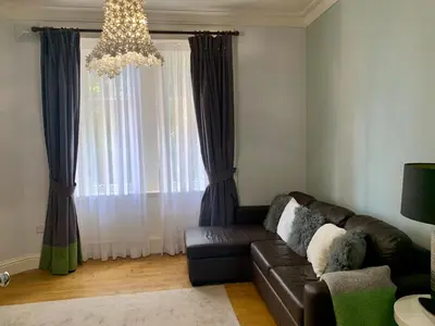 a living room with a couch and a chandelier at Pollokshields Burgh Hall Lodge Houses in Glasgow