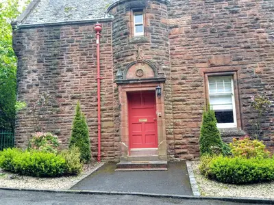 an old brick house with a red door at Pollokshields Burgh Hall Lodge Houses in Glasgow