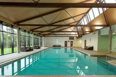a large swimming pool with blue water and windows at Isle Of Mull Hotel and Spa in Craignure