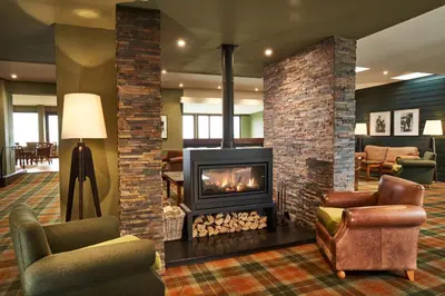 a fireplace in a living room with chairs and a couch at Isle Of Mull Hotel and Spa in Craignure