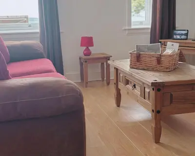 a living room with a couch and a coffee table at Honeysuckle Cottage in Killean