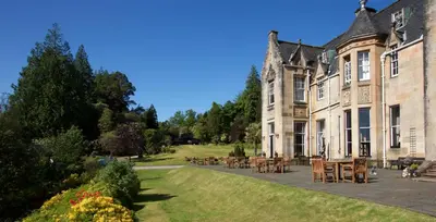 a large house with tables and chairs in the yard at Stonefield Castle Hotel ‘A Bespoke Hotel’ in Stonefield
