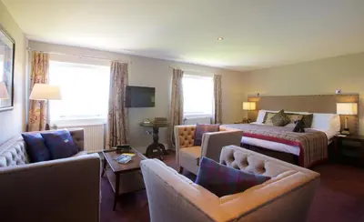 a hotel room with a bed and a couch and chairs at Stonefield Castle Hotel ‘A Bespoke Hotel’ in Stonefield