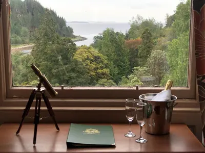 a table with a camera and wine glasses in front of a window at Stonefield Castle Hotel ‘A Bespoke Hotel’ in Stonefield