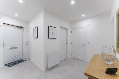 a white room with two doors and a table at Mhuilinn Apartment in Stirling