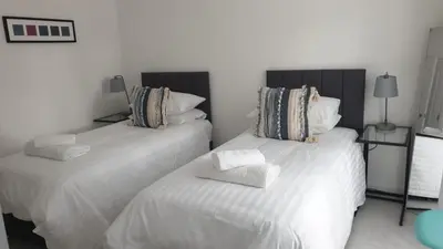 two beds in a room with white sheets and pillows at Mhuilinn Apartment in Stirling