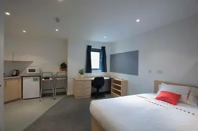 a bedroom with a bed and a desk and a kitchen at Edinburgh College Residence in Edinburgh